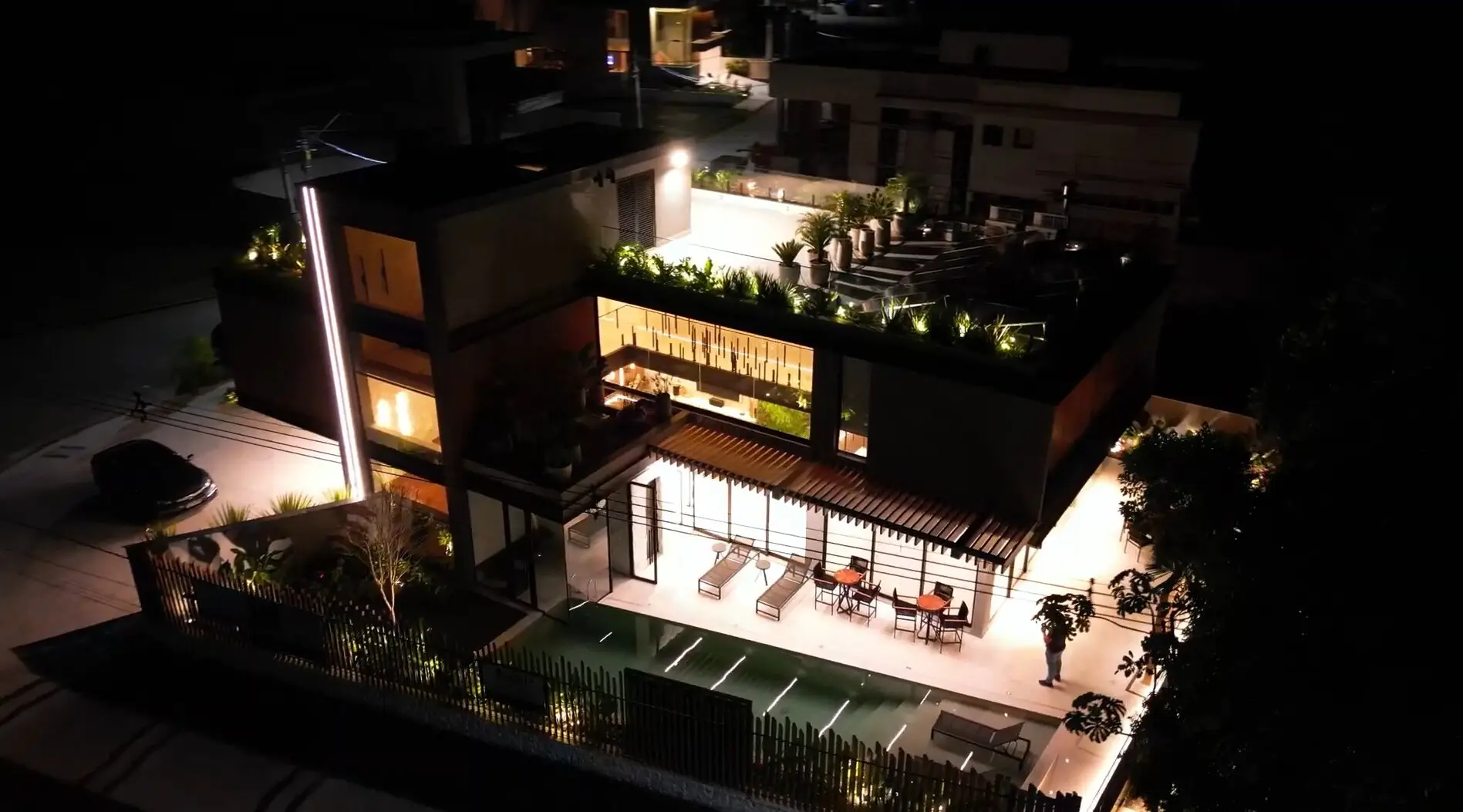 Vista aérea noturna de casa de alto padrão iluminada na Riviera de São Lourenço, Bertioga · AM&D Engenharia