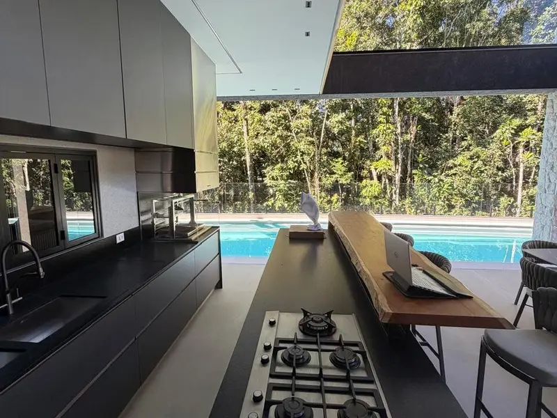 Cozinha integrada com vista para piscina e mata atlântica em casa na Riviera de São Lourenço · AM&D Engenharia